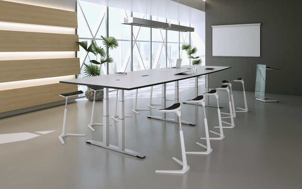 Zu viel Sitzen ist ungesund – zum Glück lassen sich die Tische der OKA Meeting Linie mit einem Elektromotor ausstatten, um sie auf Stehhöhe hinaufzufahren.